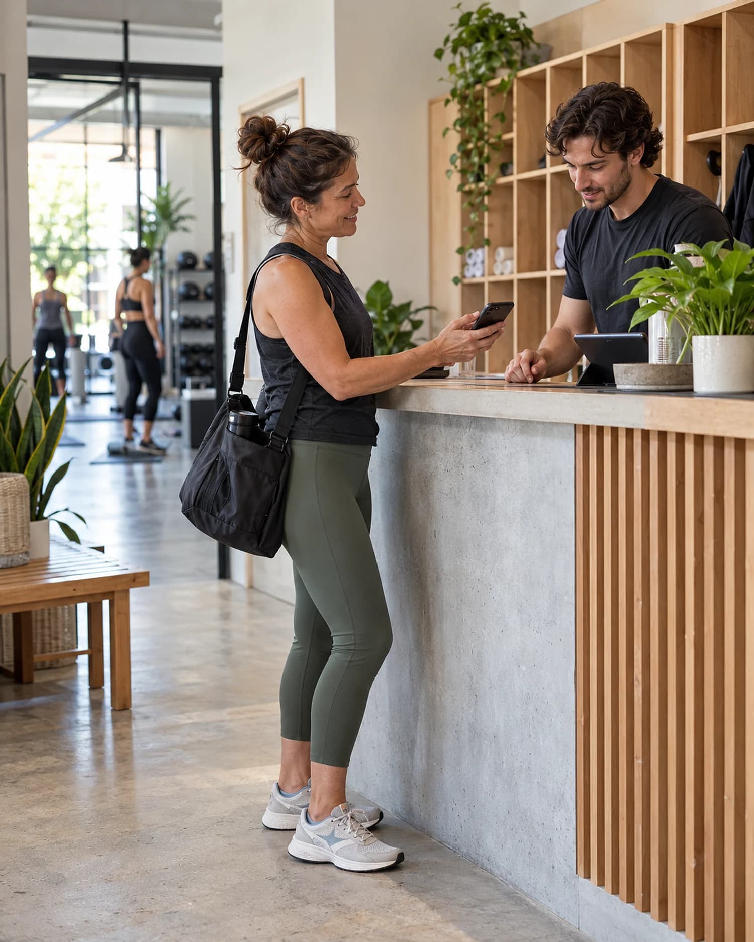 A member checks in with her phone at a fitness studio front desk