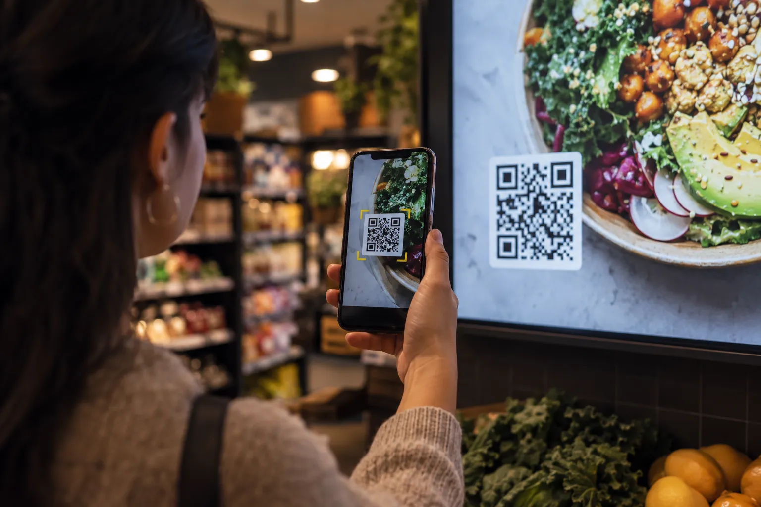 A shopper scans the QR code on an in-store screen with a phone